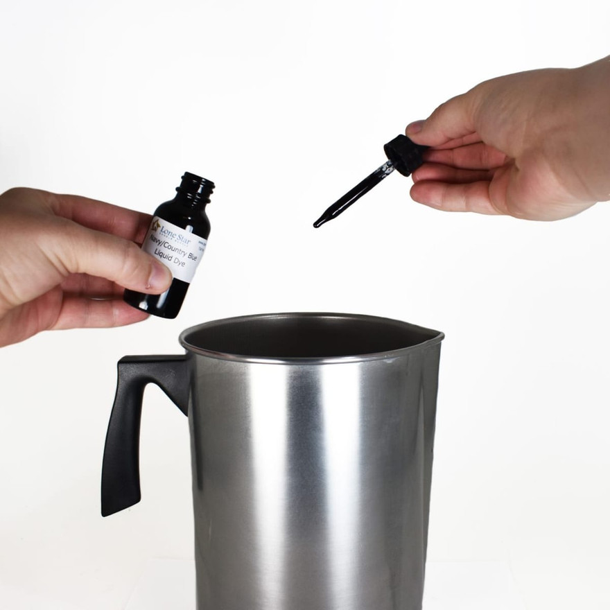 Hands holding a Navy/Country Blue liquid dye bottle and dropper above a steel pouring pot