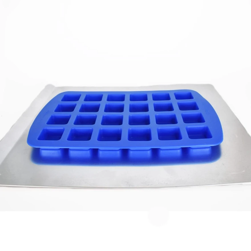 Empty blue silicone mold with 24 square cavities resting on a metal baking sheet